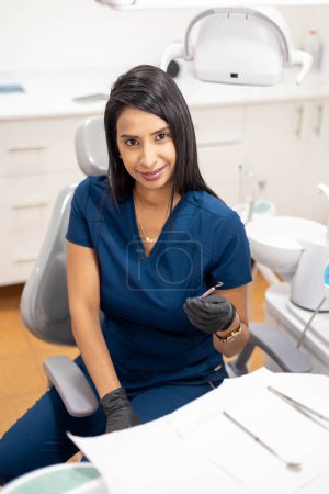 Téléchargez les photos : Belle dentiste préparant les instruments médicaux pour assister les patients dans son cabinet dentaire, mode de vie professionnel de la santé, équipement et traitements - en image libre de droit
