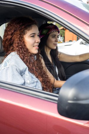 Foto de Viajando en un coche, estilo de vida y transporte, retrato de dos mujeres latinas jóvenes con el pelo rizado y recto lleva una diadema de color - Imagen libre de derechos