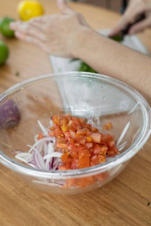 Foto de Preparar ensalada saludable, picar cebollas frescas y tomates, ingredientes nutritivos, tareas domésticas en la cocina - Imagen libre de derechos