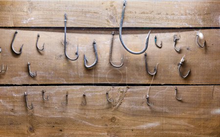 Foto de Ganchos de pesca de diferentes tamaños fijados a la madera - Imagen libre de derechos