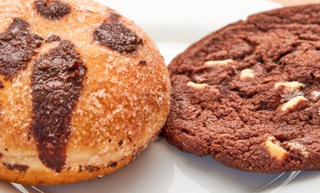 Photo for Chocolate cream-filled bun and chocolate almond cookie on a plate. Selective focus. - Royalty Free Image