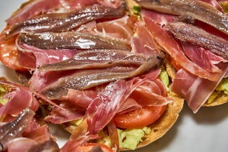 Photo for Suggestive Iberian ham toasts, tomato slices and fresh avocado. - Royalty Free Image
