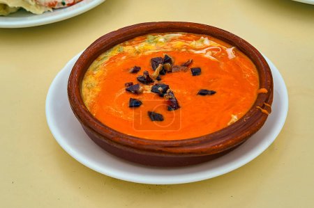 Photo for A "tapa" of salmorejo served in an earthenware dish with a few slices of serrano ham on top, served in a bar in Cadiz (Spain). - Royalty Free Image