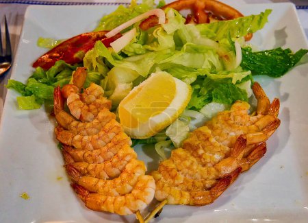 Photo for Combination dish of grilled shrimp skewers, with salad and lemon dressing, in a bar in Cadiz (Spain). - Royalty Free Image