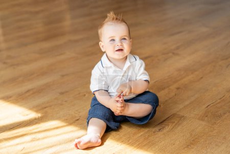 Un bébé est assis sur le sol, regardant vers le haut avec curiosité.