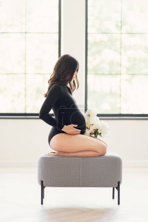 Téléchargez les photos : Une femme enceinte assise sur un lit. - en image libre de droit