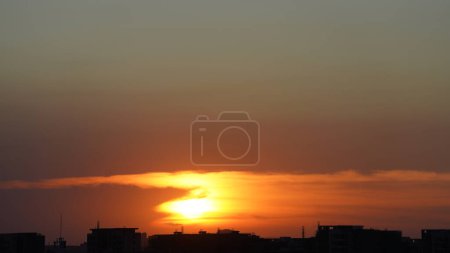 La vue magnifique sur le coucher du soleil avec la silhouette des bâtiments et le ciel de couleur orange comme arrière-plan dans la ville