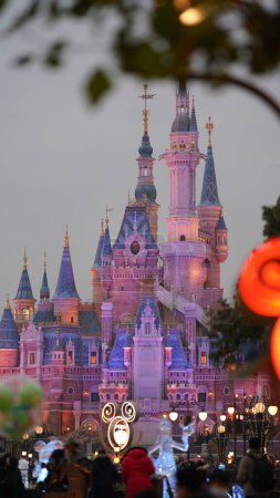 Foto de La vista del castillo de Disney con los edificios coloridos y luces encendidas - Imagen libre de derechos