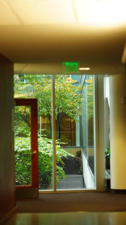 Foto de La vista interior del edificio con la ventana de vidrio transparente y el pasillo en el día lluvioso - Imagen libre de derechos