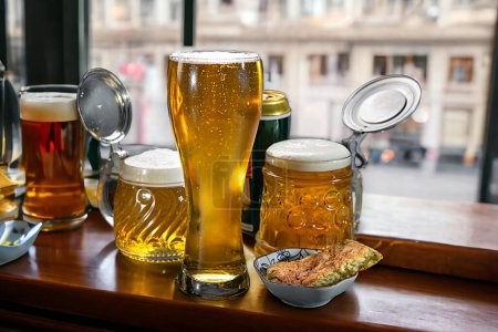 Téléchargez les photos : La bière dans un verre à bière et des tasses à bière se tiennent sur la fenêtre d'un pub. Bière. - en image libre de droit