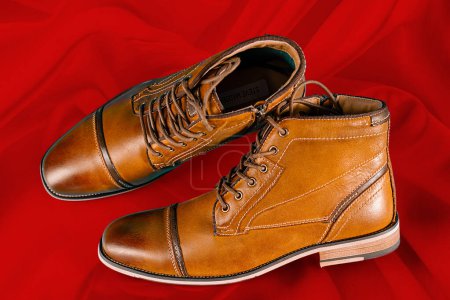 Un par de botas de piel de becerro premium sobre un fondo rojo. Disparo horizontal. Ideas de zapatos para hombre.
