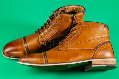 Un par de botas de piel de becerro premium sobre un fondo verde. Disparo horizontal. Ideas de zapatos para hombres.
