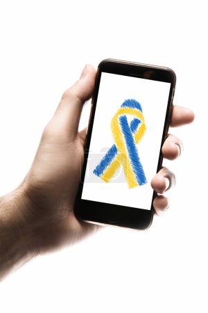 Foto de Teléfono inteligente en las manos en la pantalla cinta azul y amarillo, ayuda y donación a Ucrania en la guerra. concepto necesita ayuda y apoyo, la verdad va a ganar - Imagen libre de derechos