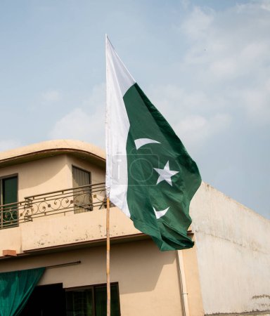 Foto de La bandera nacional de Pakistán ondeando en el cielo azul con nubes, la bandera paquistaní en Nubes fondo cielo azul. - Imagen libre de derechos