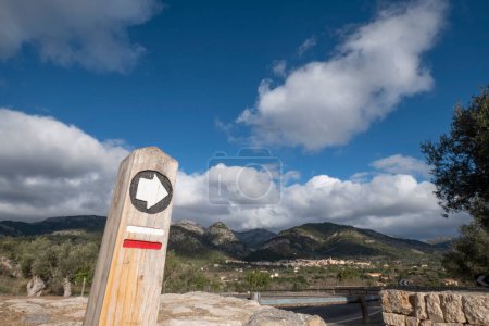 Photo for Dry stone route, GR221, signpost with the town in the background and sky with cotton clouds, Caimari , Majorca, Balearic Islands, Spain - Royalty Free Image