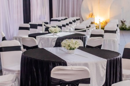 Foto de Decoración del lugar de recepción de la boda en el interior con una ordenada disposición de mesas y sillas - Imagen libre de derechos