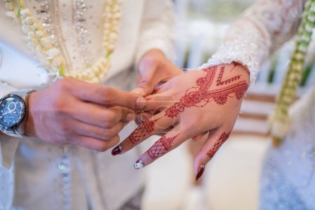 Ein Ehepaar steckte sich bei einer traditionellen indonesischen Hochzeitszeremonie gegenseitig die Eheringe an. Der Bräutigam legt seiner geliebten Frau einen Ring an den Finger. Das Paar tauschte Eheringe. Gerade verheiratet