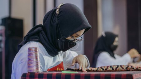 Photo for Bandar Lampung, Lampung-Indonesia 21 November 2021: A woman is weaving cloth, or so-called traditional tapis cloth, typical of Lampung province, by hand - Royalty Free Image