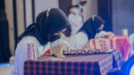 Photo for Bandar Lampung, Lampung-Indonesia 21 November 2021: A woman is weaving cloth, or so-called traditional tapis cloth, typical of Lampung province, by hand - Royalty Free Image