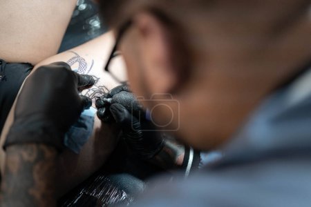 Foto de Un tatuador está tatuando una serpiente en una pierna de mujer. De cerca. Concepto de estudio de tatuaje - Imagen libre de derechos
