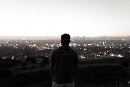 Téléchargez les photos : A view of Los Angeles cityscape with a blurred young man looking during the sunset in Baldwin Hills, Los Angeles. Concept of lifestyle - en image libre de droit