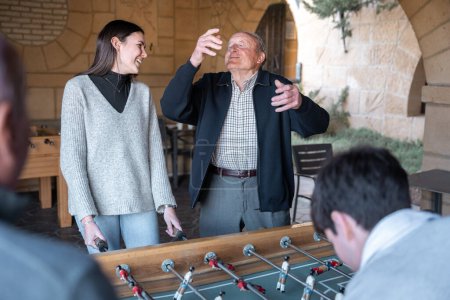 Photo for A granddaugther and grandfather are having fun after being scored in table football. Concept of family fun time - Royalty Free Image