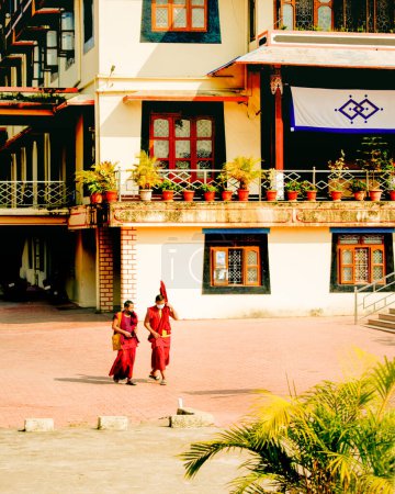 Photo for "Mundgod, Karnataka,India- 6th February 2022: Tibetan old monks in red color clothing wearing masks,walking on the infront of Buddhist monastery" - Royalty Free Image