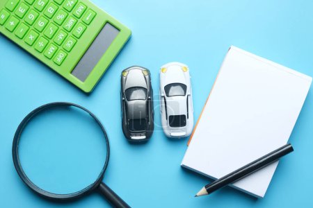 Téléchargez les photos : Flatlay picture of magnifying two cars miniature, notepad,pencil and calculator. Best deal car to drive. - en image libre de droit