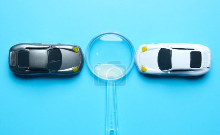 Téléchargez les photos : Flatlay picture of two miniature cars with magnifying glass insight. Best car deal concept. - en image libre de droit