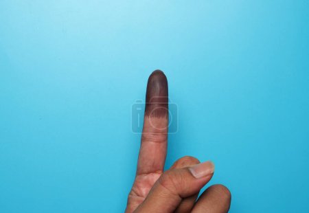Photo for A picture of finger with indelible ink on blue background. Confirmation voting during Malaysia General Elections. - Royalty Free Image
