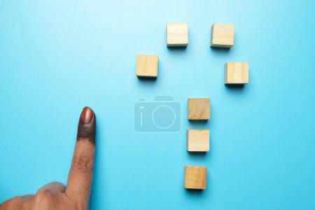 Photo for A picture of finger with finger in general elections indelible ink and wooden block question mark. Country directionn after general elections. - Royalty Free Image