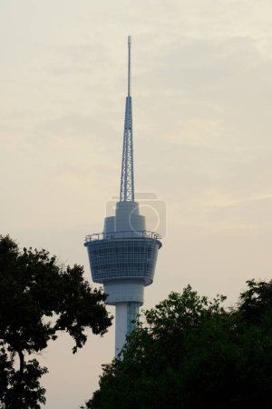 Téléchargez les photos : "Kuantan, Malaisie- 31 août 2023 : Photo sélective du sommet de la tour Kuantan 188 entre les arbres au lever du soleil." - en image libre de droit