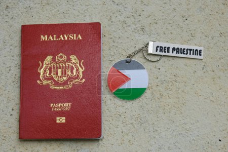 Téléchargez les photos : "Klang, Malaisie 1 novembre 2023 : Une photo de Malaisie Passeport avec drapeau palestinien libre porte-clés sur fond rugueux." - en image libre de droit
