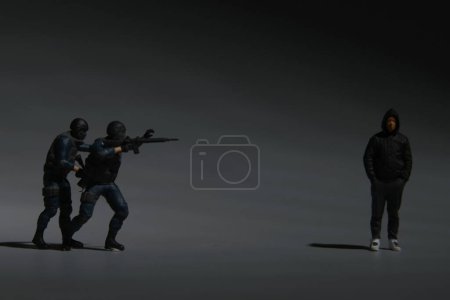 Téléchargez les photos : Une image en faible luminosité de la police anti-terroriste et des hommes avec capuche miniature. Arrêter la cybercriminalité - en image libre de droit