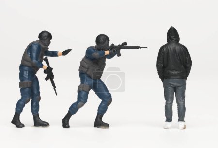 Foto de Un primer plano de la miniatura de la fuerza antiterrorista arrestando a hombres en miniatura en el capó. Detener el crimen y la violencia. - Imagen libre de derechos