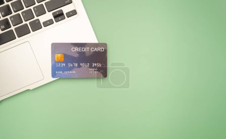Photo for Top view of a blue credit card over on a laptop isolated on a green background with copy space for text. Business and finance concept. - Royalty Free Image