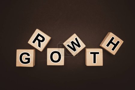 Business growth and strategy marketing concept. Overhead view of wooden cubes with words "GROWTH" over a black background