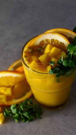 Foto de Un vaso alto de batido de naranja recién mezclado está adornado con una rebanada de naranja y una ramita de perejil, creando una bebida refrescante.. - Imagen libre de derechos