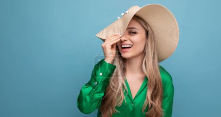 Téléchargez les photos : Élégant jeune femme touriste en vacances dans un chapeau de paille d'été sur un fond de studio bleu. - en image libre de droit