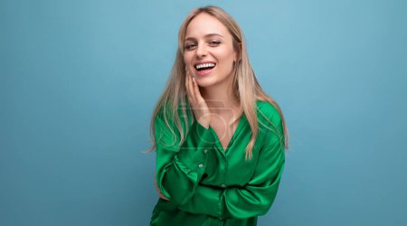 Téléchargez les photos : Femme souriante en vacances en chemise verte posant sur fond bleu studio. - en image libre de droit