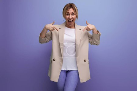 Foto de Primer plano de una mujer de negocios rubia sonriente positiva en una chaqueta exitosa en el trabajo en el fondo con espacio para copiar. - Imagen libre de derechos