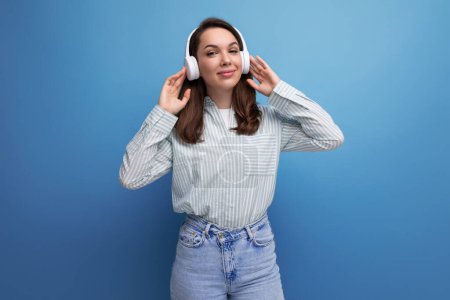 Téléchargez les photos : 20s brunette dame dans un style informel reposant écouter de la musique à travers des écouteurs. - en image libre de droit