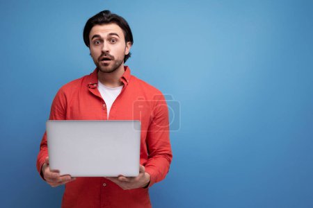 Téléchargez les photos : Beau caucasien brunette jeune homme d'affaires tenant un ordinateur portable dans ses mains. - en image libre de droit