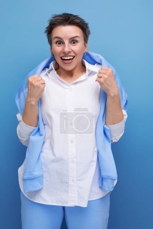 Téléchargez les photos : Photo verticale d'une élégante jeune femme à la mode avec des cheveux touffus dans une chemise blanche dans un cadre informel. - en image libre de droit
