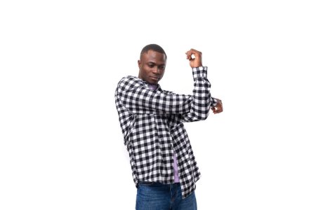 Foto de Retrato de un chico africano guapo de 30 años vestido con una camisa a cuadros bailando sobre el fondo con espacio para copiar. - Imagen libre de derechos