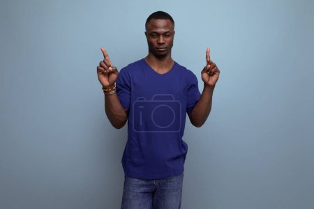 Foto de Agradable joven americano en camiseta azul señalando con el dedo a tener una idea. - Imagen libre de derechos