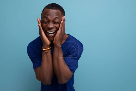 Téléchargez les photos : Beau jeune homme africain en t-shirt bleu souriant. - en image libre de droit