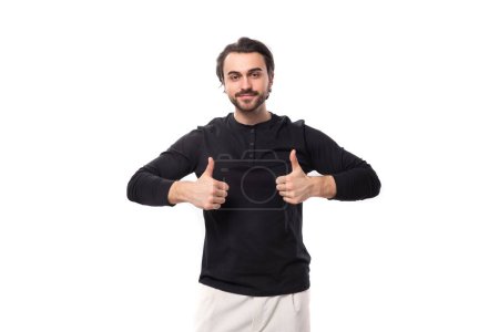 Téléchargez les photos : Jeune beau brunet homme européen en sweat-shirt noir avec maquette sur fond blanc isolé. - en image libre de droit