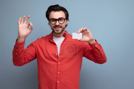 Téléchargez les photos : Smart beau jeune homme brune avec des lunettes annonce une carte bancaire. - en image libre de droit