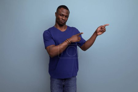 Téléchargez les photos : Beau jeune américain mâle adulte pointant doigt à ad mur. - en image libre de droit